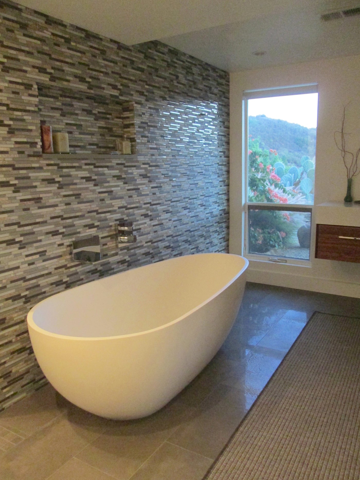 Badeloft BW-01 freestanding bathtub in a customer bathroom with a mosaic-tile wall.
