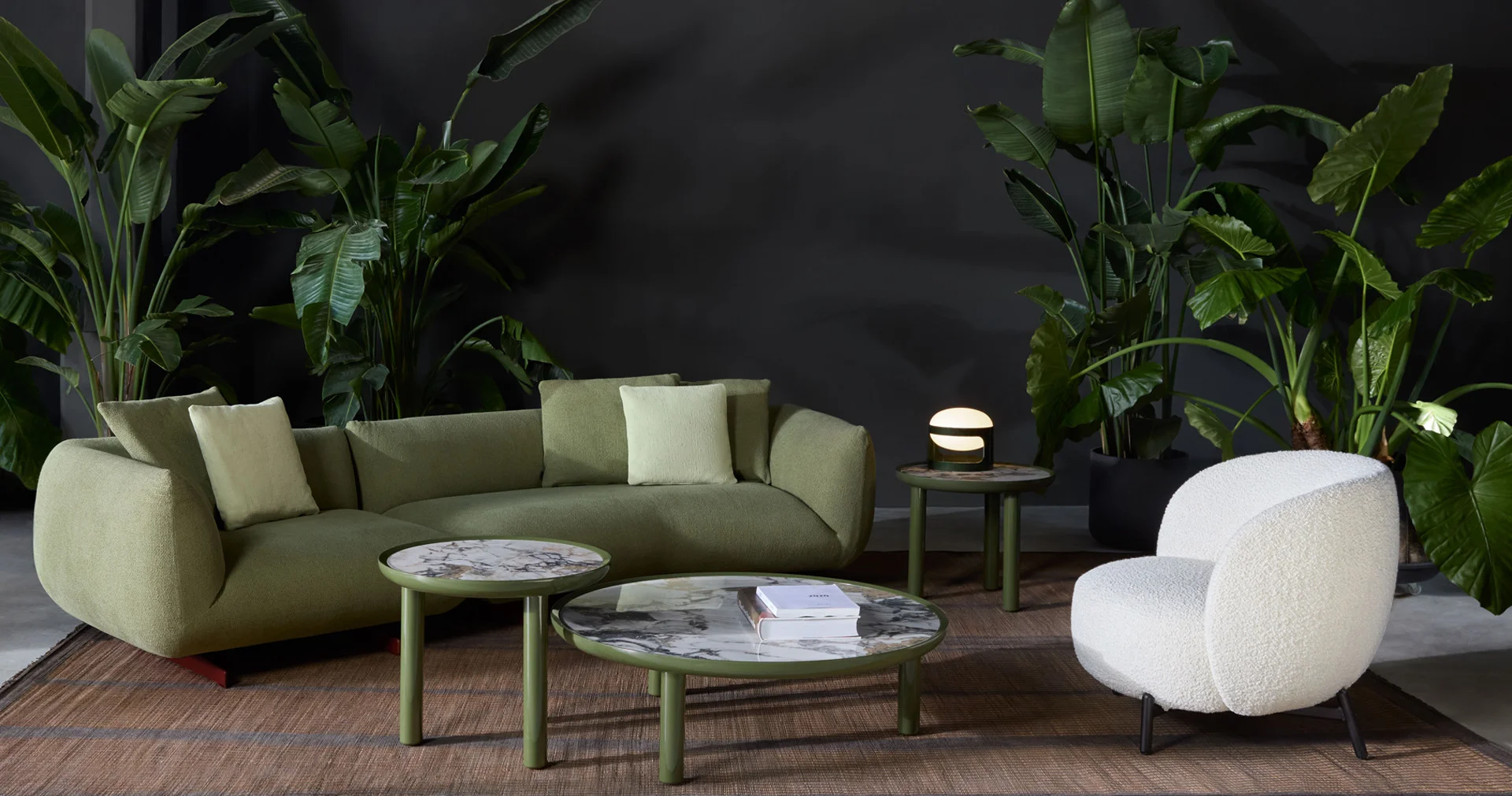 Kartell living-room collection with a green sofa, white armchair and round coffee tables.