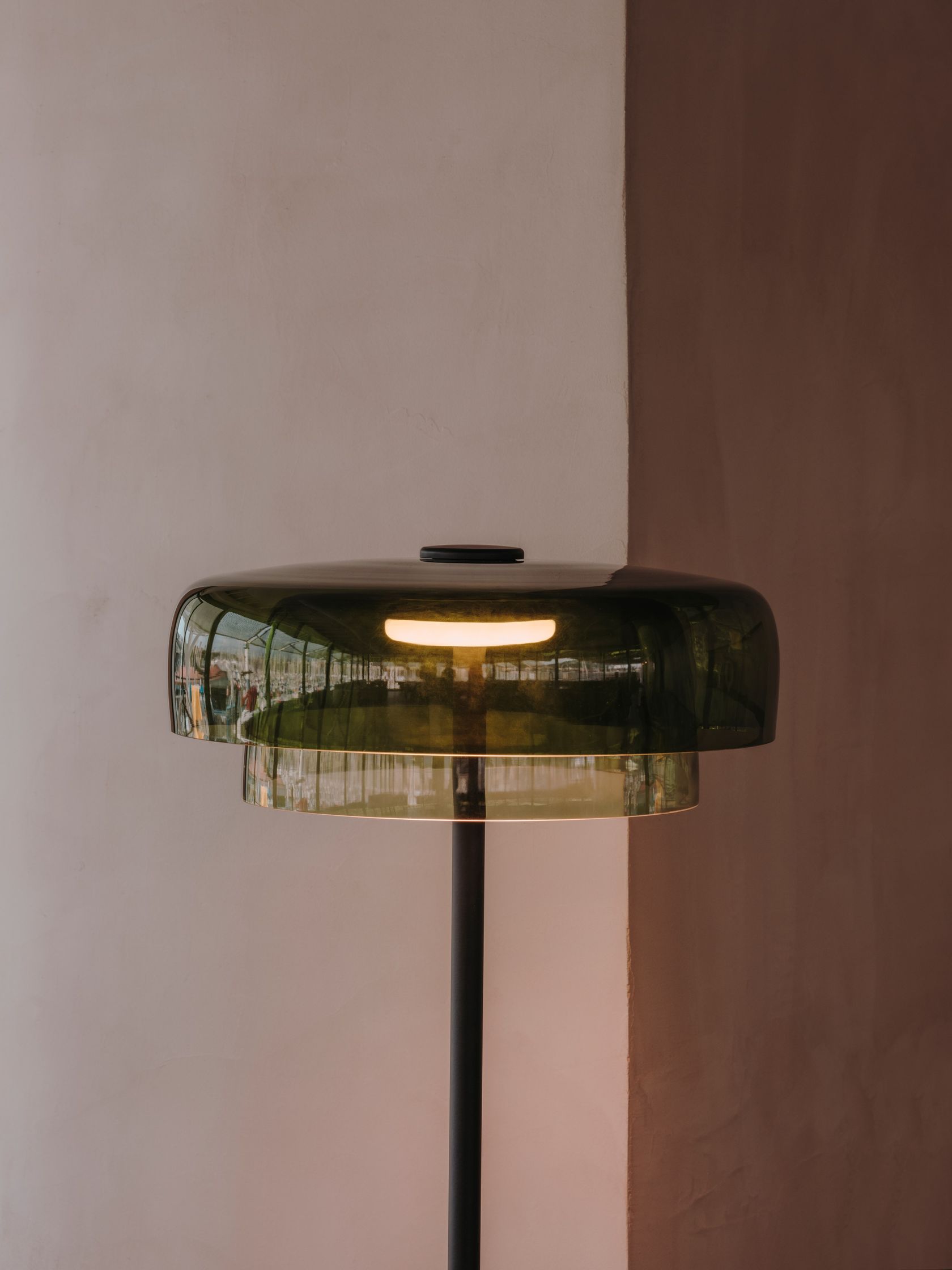 Close-up of the illuminated LedsC4 Levels floor lamp with overlapping green glass shades