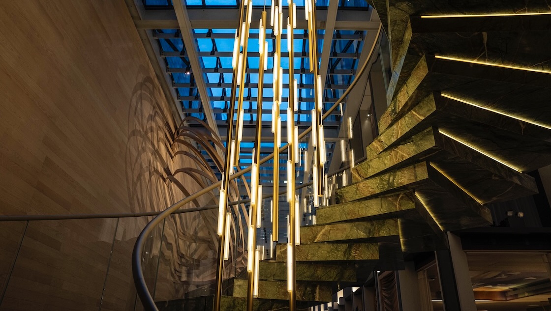 Lee Broom illuminated pendants cascading beside a sculptural stone staircase